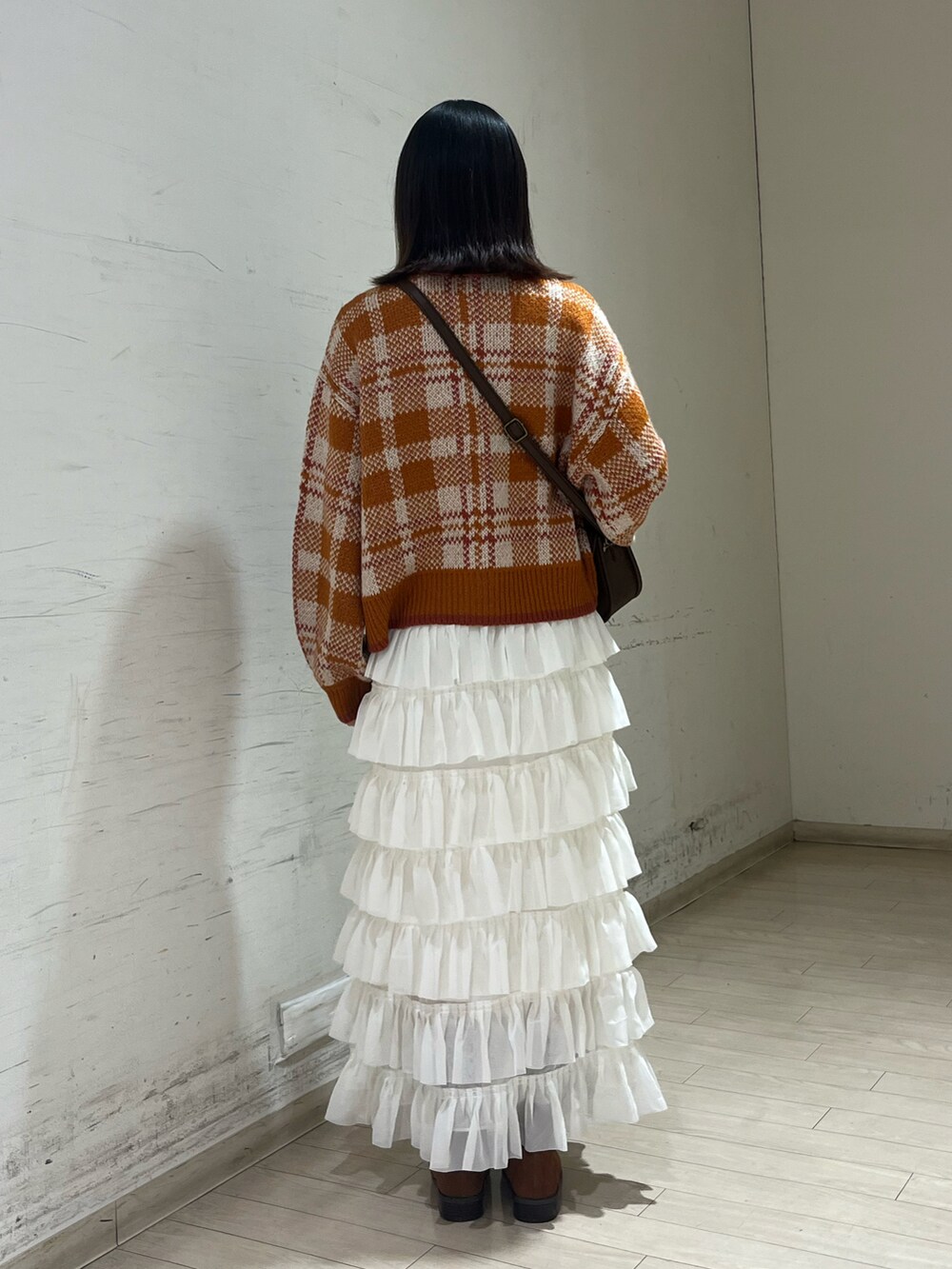 ホワイト系のスカート、オレンジ系のカーディガン/ボレロ、ブラウン系のハンドバッグを着用したレディースの秋コーディネートの2枚目の写真