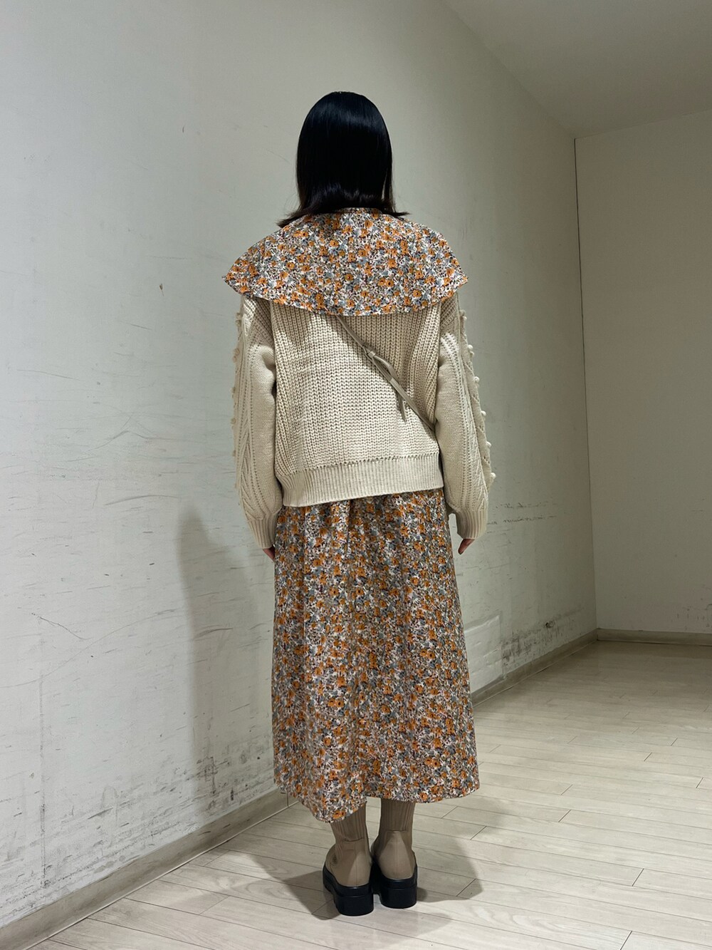 ホワイト系のニット/セーター、オレンジ系のワンピース、ベージュ系のハンドバッグを着用したレディースの秋コーディネートの2枚目の写真