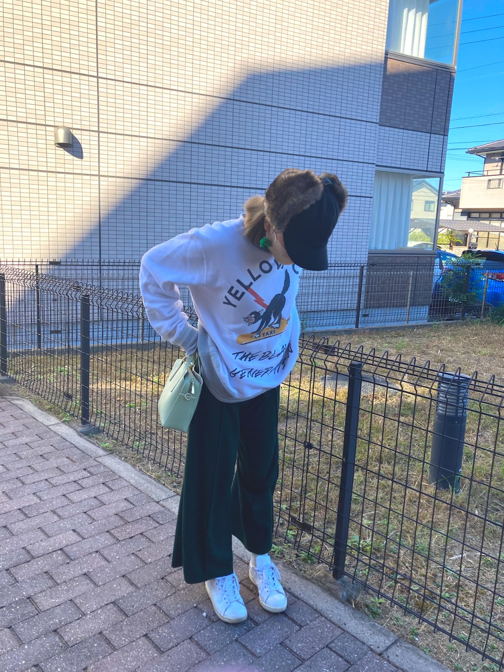 ホワイト系のスウェット、グリーン系のパンツ、ホワイト系のスニーカーを着用したレディースの秋コーディネートの2枚目の写真