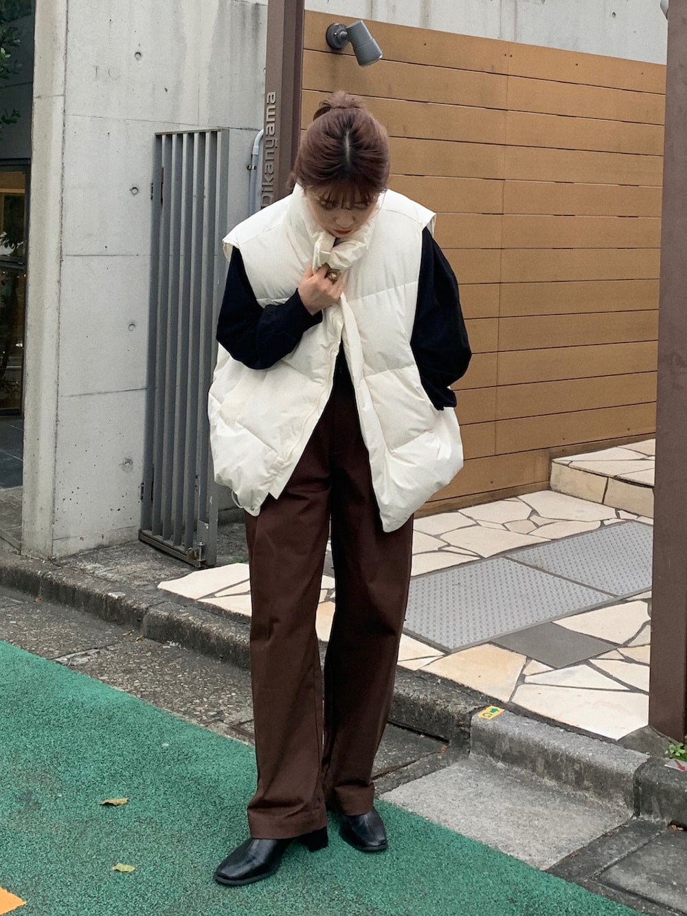 ブラック系のスウェット、ホワイト系のダウンベスト、ホワイト系のチノパンツを着用したレディースの秋コーディネートの2枚目の写真