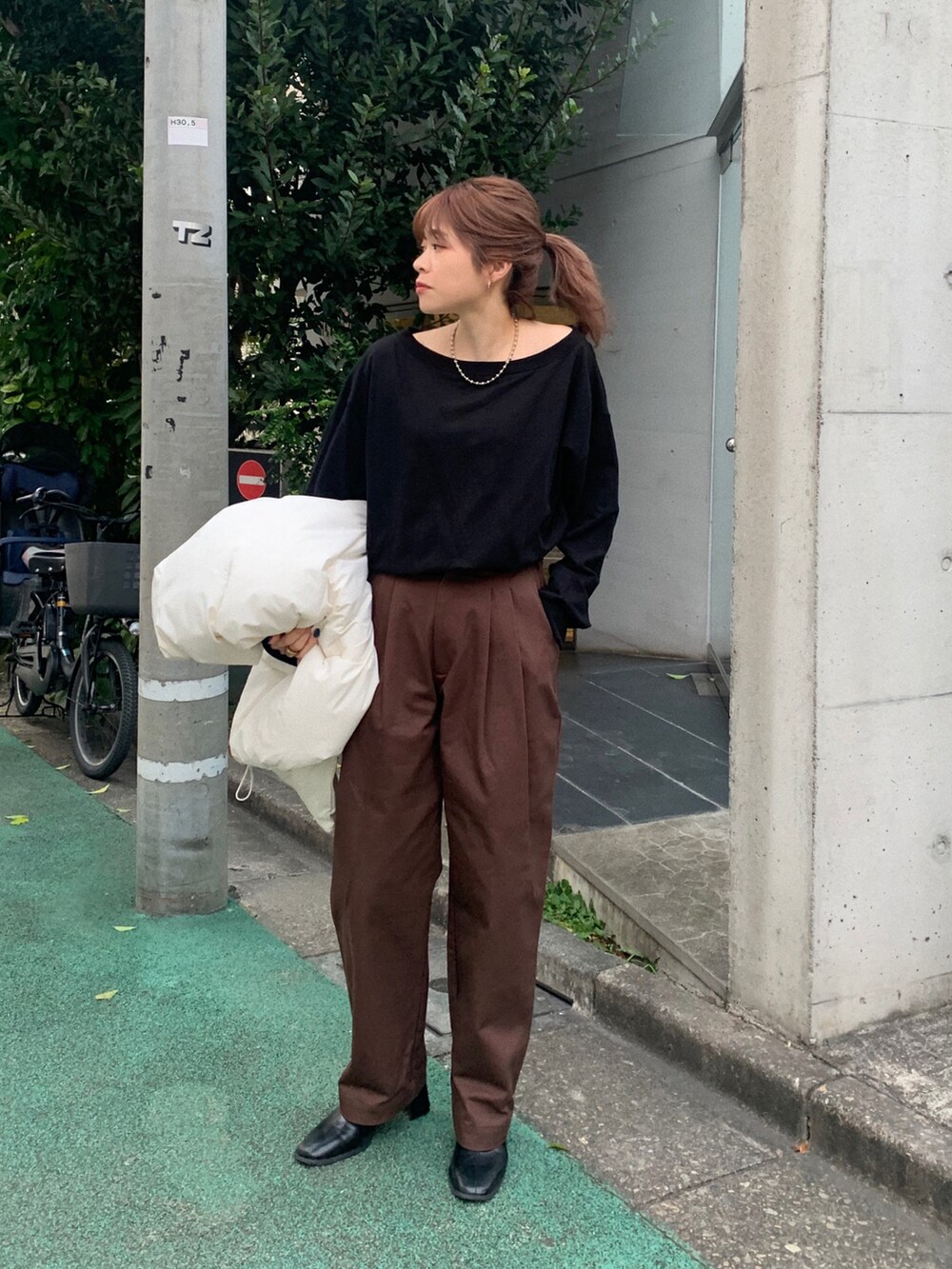 ブラック系のスウェット、ホワイト系のダウンベスト、ホワイト系のチノパンツを着用したレディースの秋コーディネートの4枚目の写真