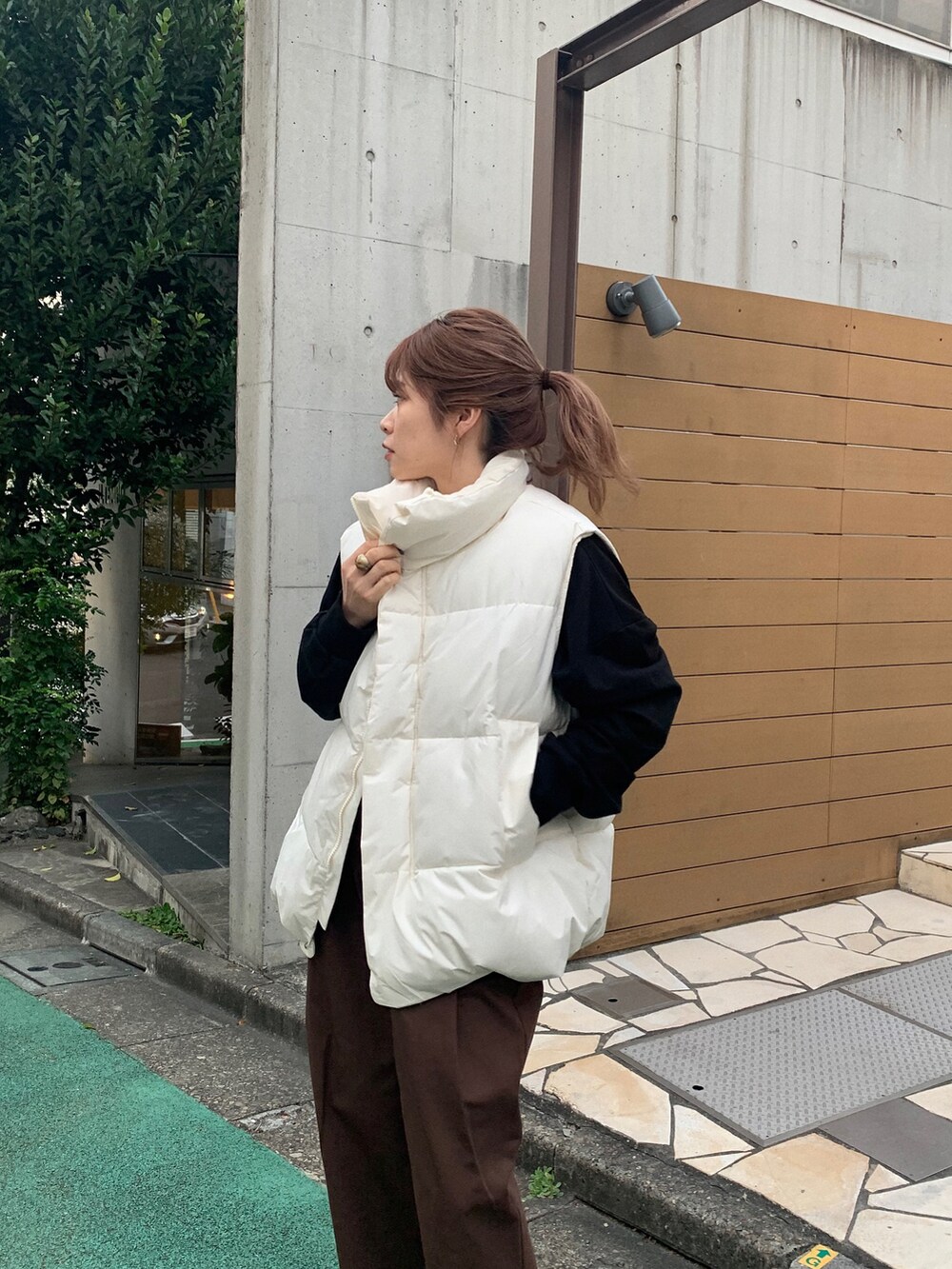 ブラック系のスウェット、ホワイト系のダウンベスト、ホワイト系のチノパンツを着用したレディースの秋コーディネートの3枚目の写真