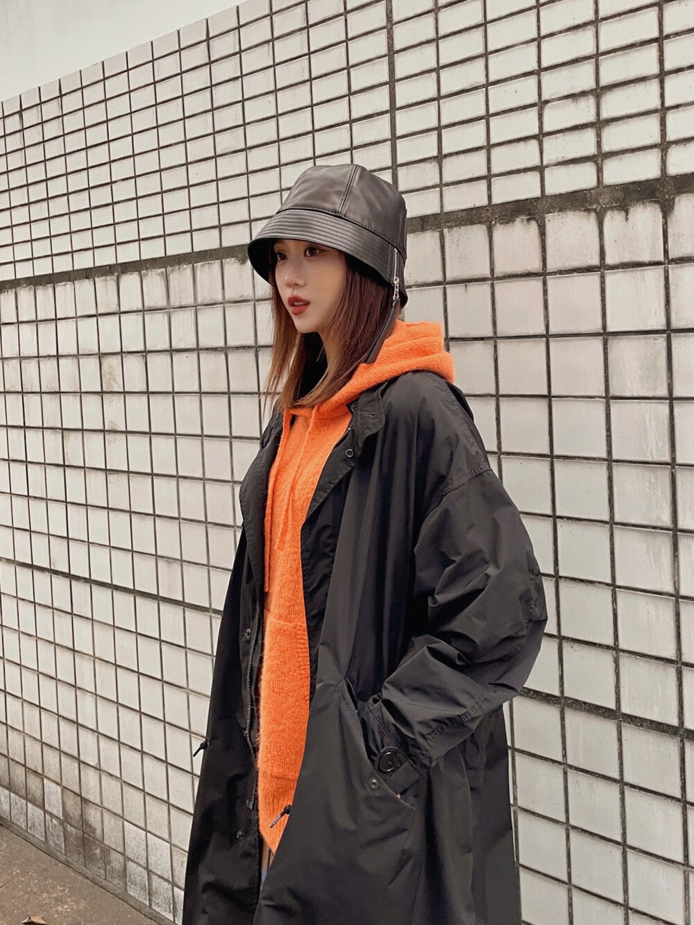 オレンジ系のニット/セーター、ブラック系のその他アウター、ブラウン系のスカートを着用したレディースの冬コーディネートの2枚目の写真