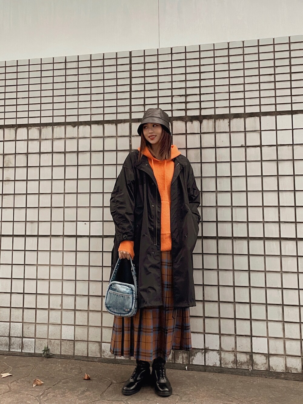 オレンジ系のニット/セーター、ブラック系のその他アウター、ブラウン系のスカートを着用したレディースの冬コーディネートの3枚目の写真