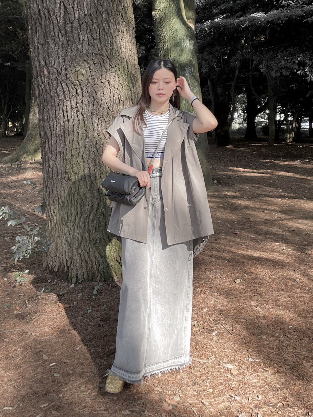 ブラック系のショルダーバッグ、ホワイト系のタンクトップ、ゴールド系のその他シューズを着用したレディースの秋コーディネートの4枚目の写真