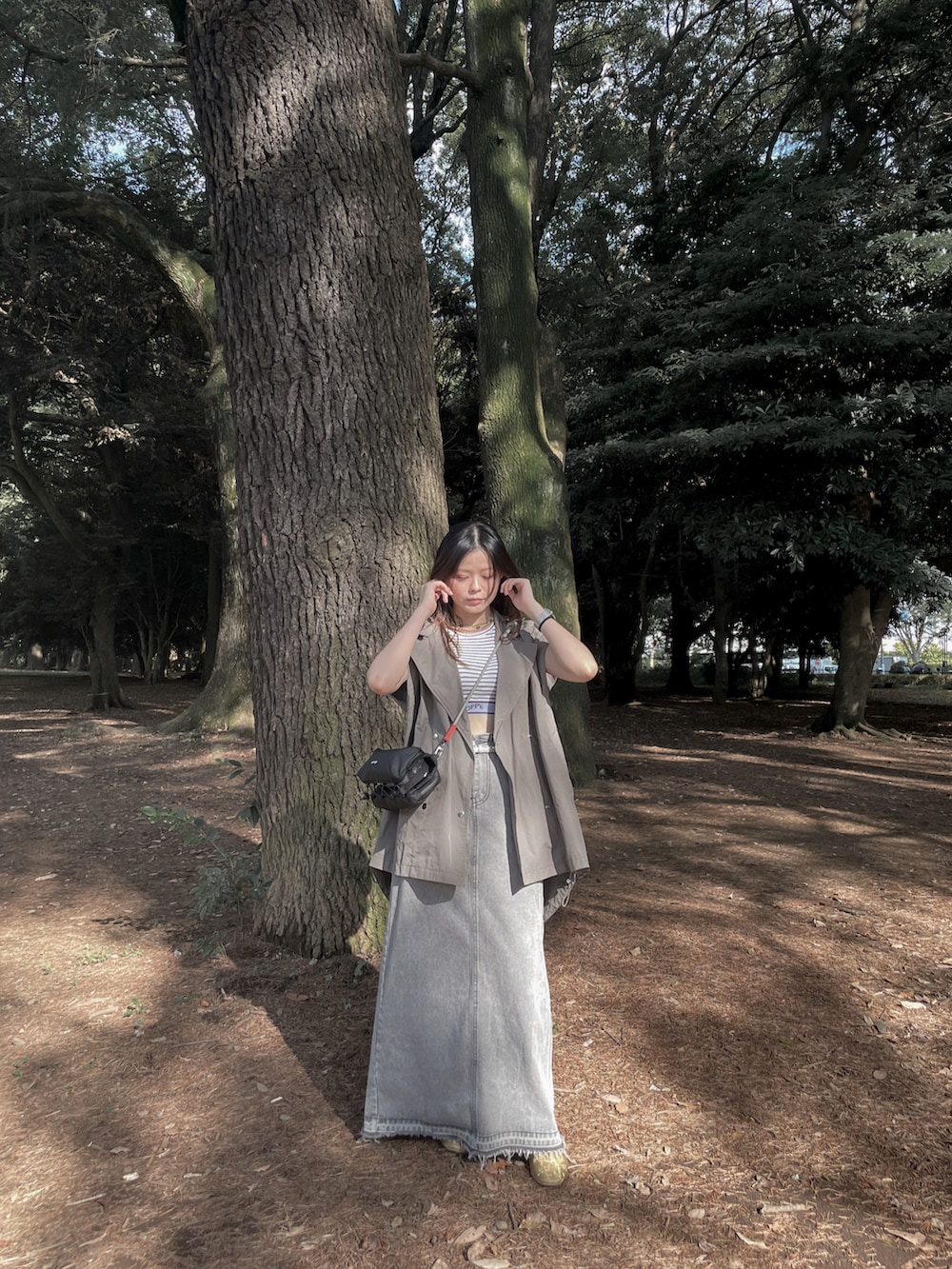 ブラック系のショルダーバッグ、ホワイト系のタンクトップ、ゴールド系のその他シューズを着用したレディースの秋コーディネートの3枚目の写真