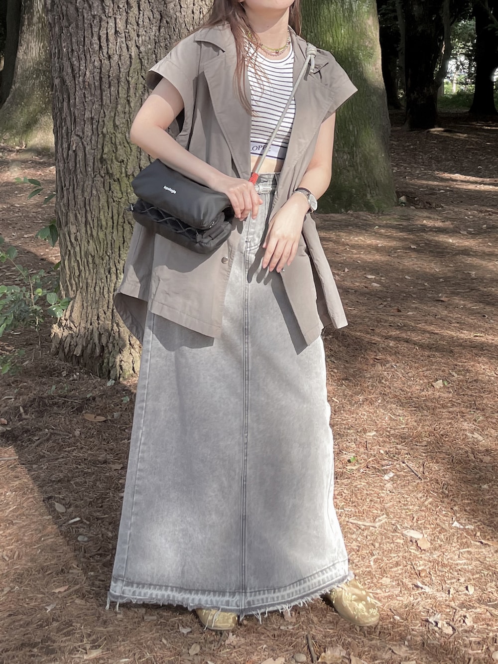 ブラック系のショルダーバッグ、ホワイト系のタンクトップ、ゴールド系のその他シューズを着用したレディースの秋コーディネートの2枚目の写真