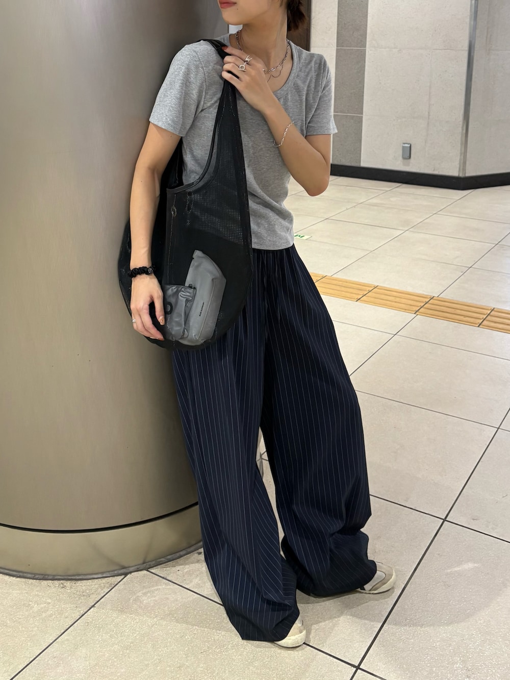 ブラック系のトートバッグ、グレー系のTシャツ/カットソー、ブルー系のスラックスを着用したレディースの夏コーディネートの2枚目の写真