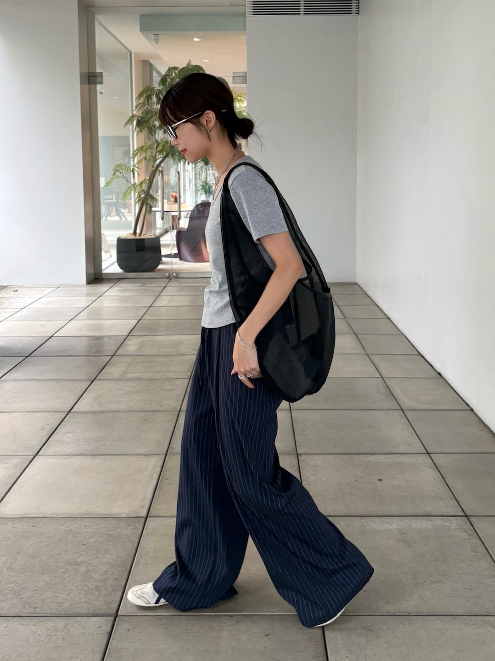 ブラック系のトートバッグ、グレー系のTシャツ/カットソー、ブルー系のスラックスを着用したレディースの夏コーディネートの3枚目の写真