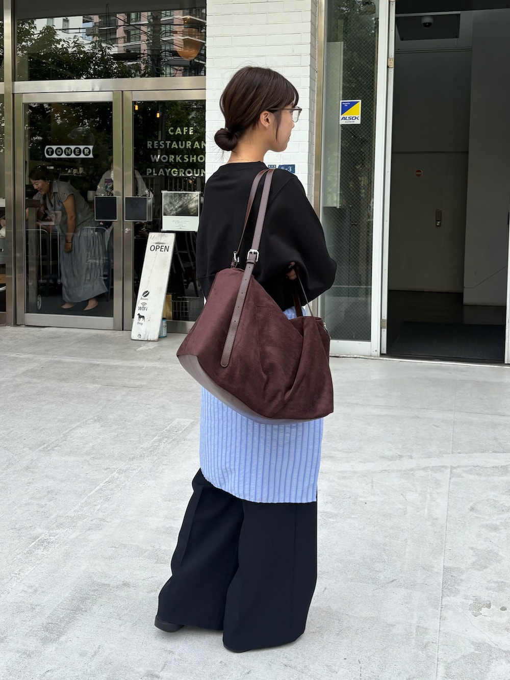 ブラック系のスウェット、ブラウン系のショルダーバッグ、ブルー系のシャツ/ブラウスを着用したレディースの秋コーディネートの2枚目の写真