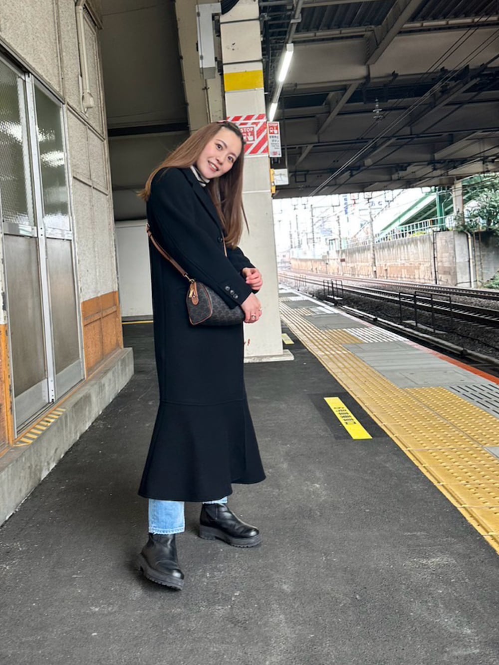 ブラック系のブーツ、ブルー系のデニムパンツ、ブラウン系のバッグを着用したレディースの冬コーディネートの2枚目の写真