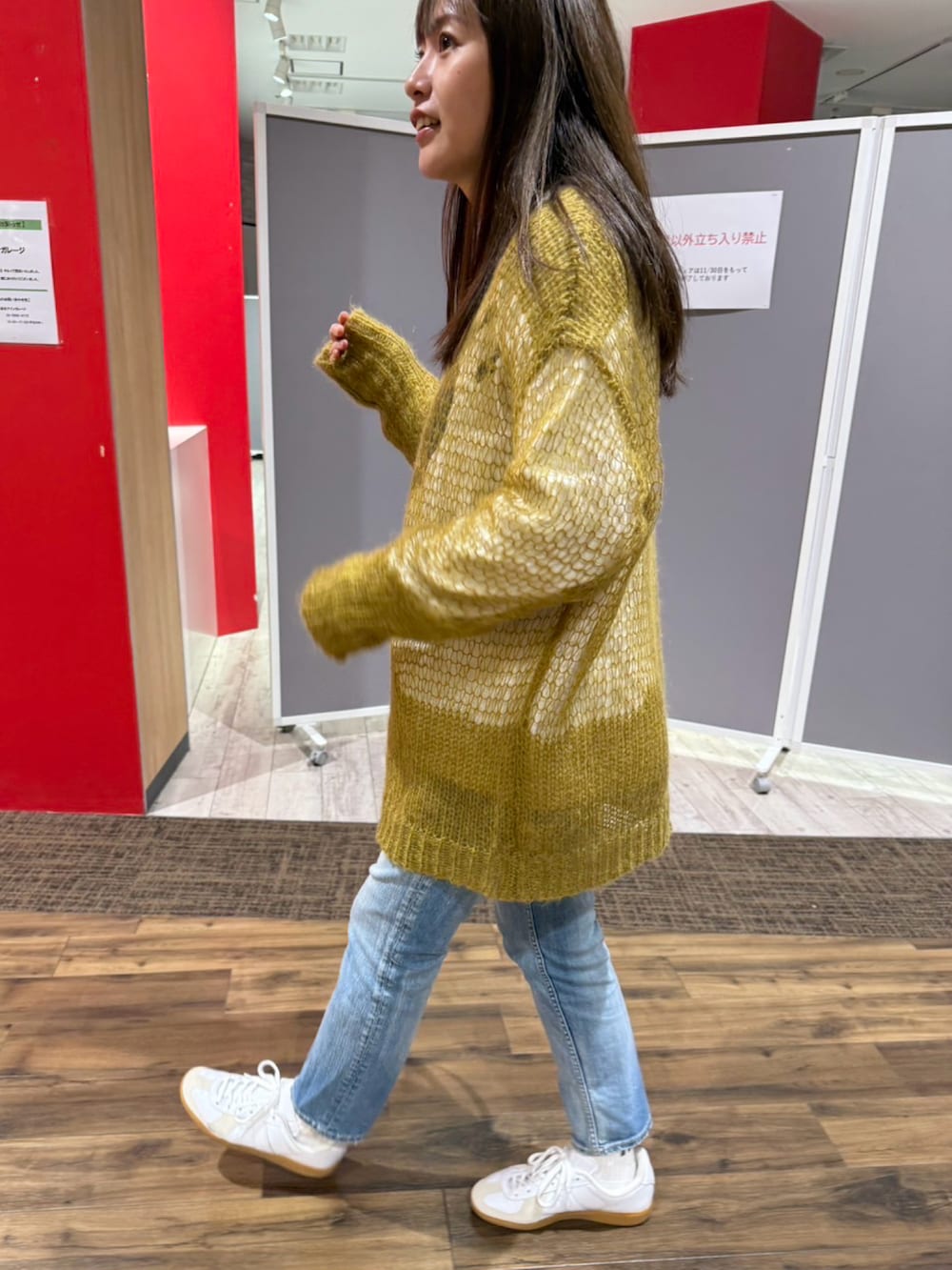 ブルー系のデニムパンツ、ホワイト系のスニーカー、グリーン系のニット/セーターを着用したレディースの冬コーディネートの2枚目の写真