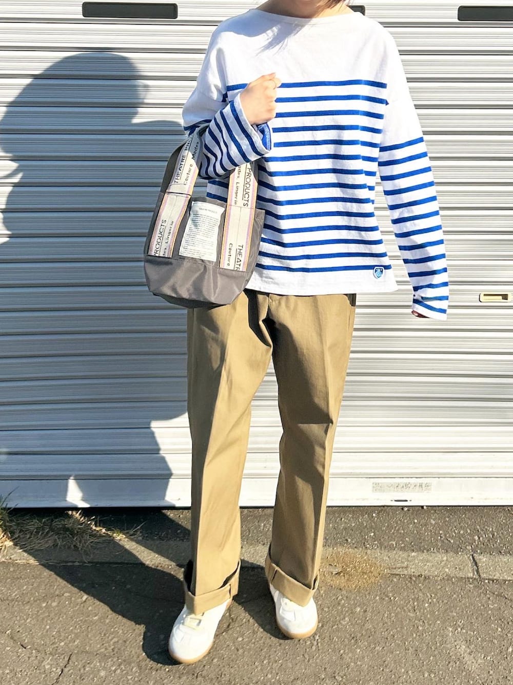 ブラック系のTシャツ/カットソー、ベージュ系のトートバッグ、ベージュ系のチノパンツを着用したレディースの春コーディネートの2枚目の写真