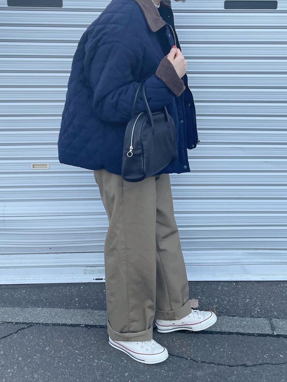 ベージュ系のチノパンツ、ホワイト系のスニーカー、ブラック系のボストンバッグを着用したレディースの冬コーディネートの3枚目の写真