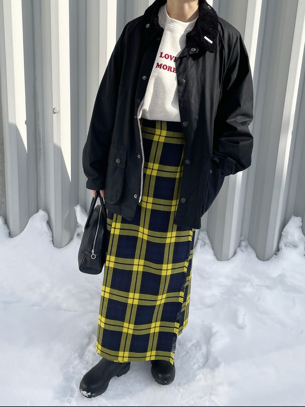 ブラック系のブルゾン、イエロー系のスカート、ブラック系のボストンバッグを着用したレディースの冬コーディネートの3枚目の写真