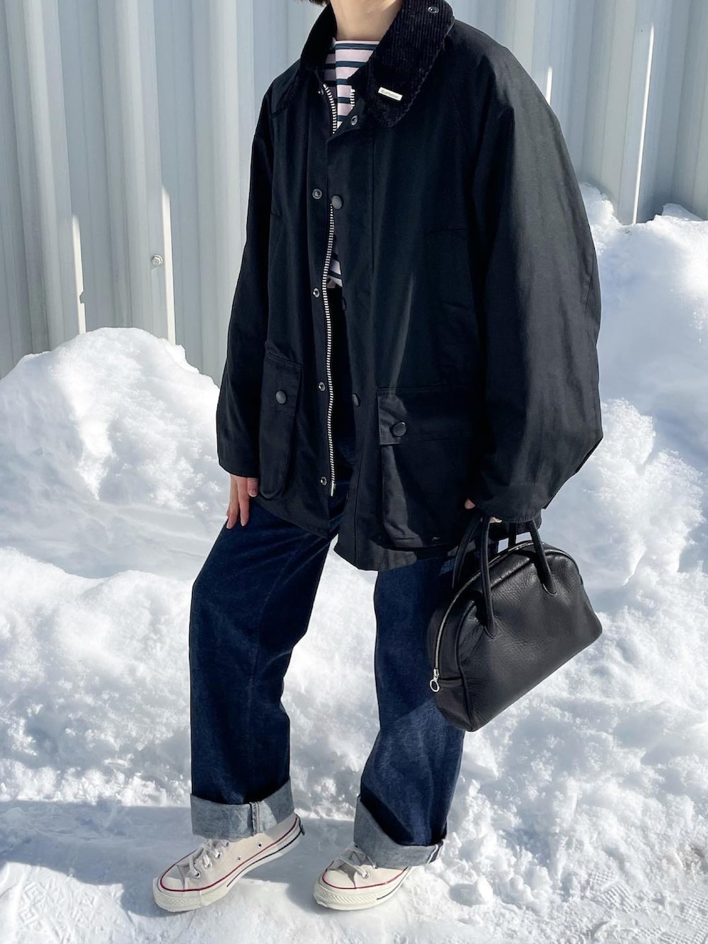 ブルー系のデニムパンツ、ブラック系のボストンバッグ、ホワイト系のスニーカーを着用したレディースの冬コーディネートの3枚目の写真