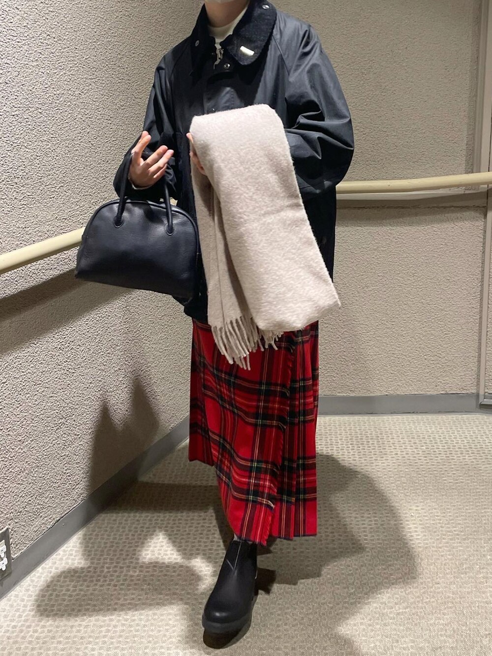 ブラック系のブルゾン、レッド系のスカート、ブラック系のブーツを着用したレディースの冬コーディネートの4枚目の写真