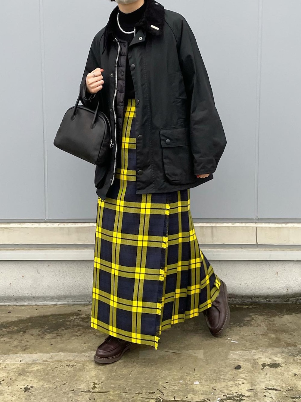 ブラック系のニット/セーター、イエロー系のスカート、ブラウン系のドレスシューズを着用したレディースの秋コーディネートの3枚目の写真