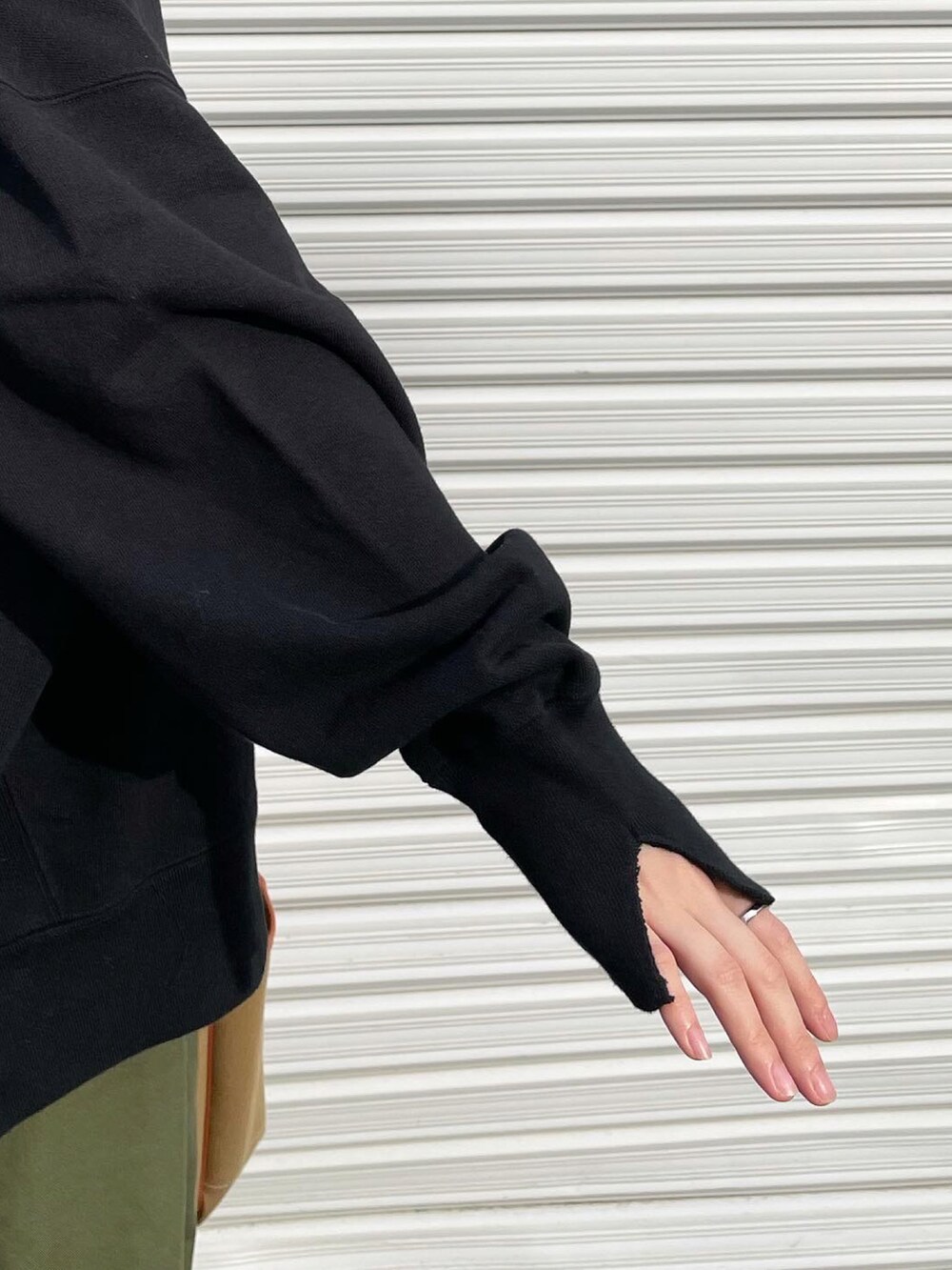 ブラック系のスウェット、ブラウン系のハンドバッグ、ブルー系のスニーカーを着用したレディースの秋コーディネートの2枚目の写真