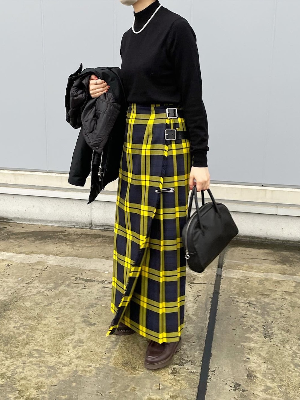 ブラック系のニット/セーター、イエロー系のスカート、ブラウン系のドレスシューズを着用したレディースの秋コーディネートの5枚目の写真