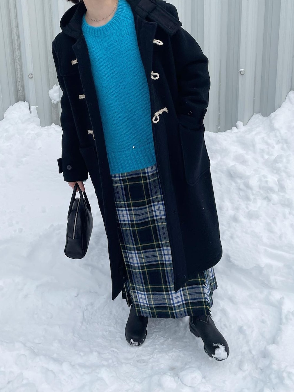 ブルー系のニット/セーター、ブラック系のボストンバッグ、グリーン系のスカートを着用したレディースの冬コーディネートの3枚目の写真