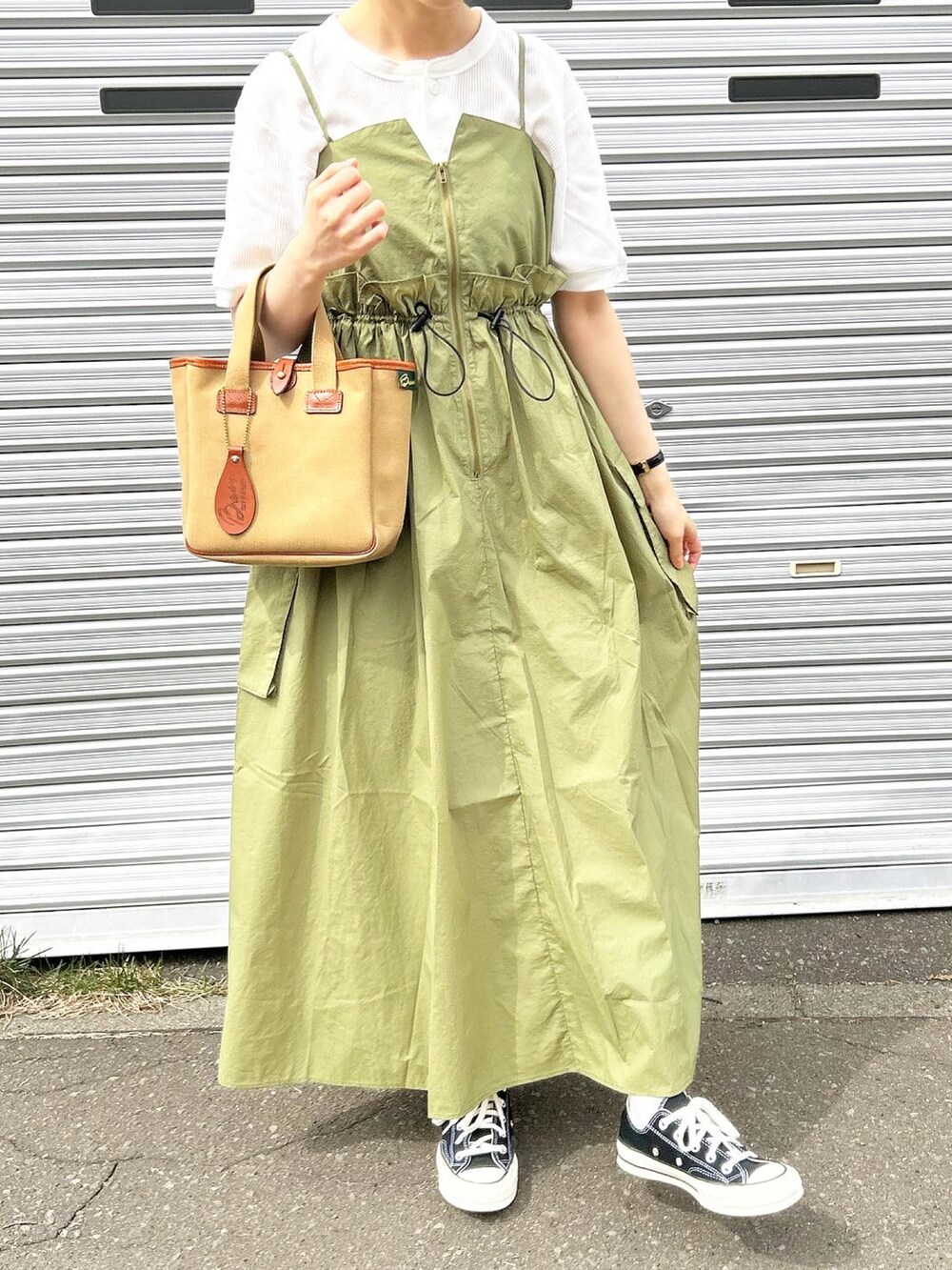 グリーン系のワンピース、ブラウン系のハンドバッグ、ブラック系のスニーカーを着用したレディースの春コーディネートの3枚目の写真