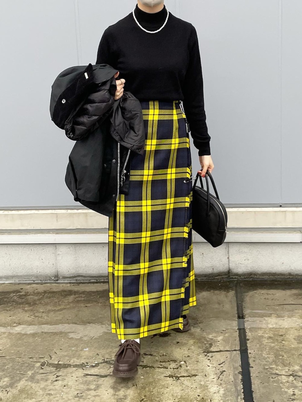 ブラック系のニット/セーター、イエロー系のスカート、ブラウン系のドレスシューズを着用したレディースの秋コーディネートの2枚目の写真