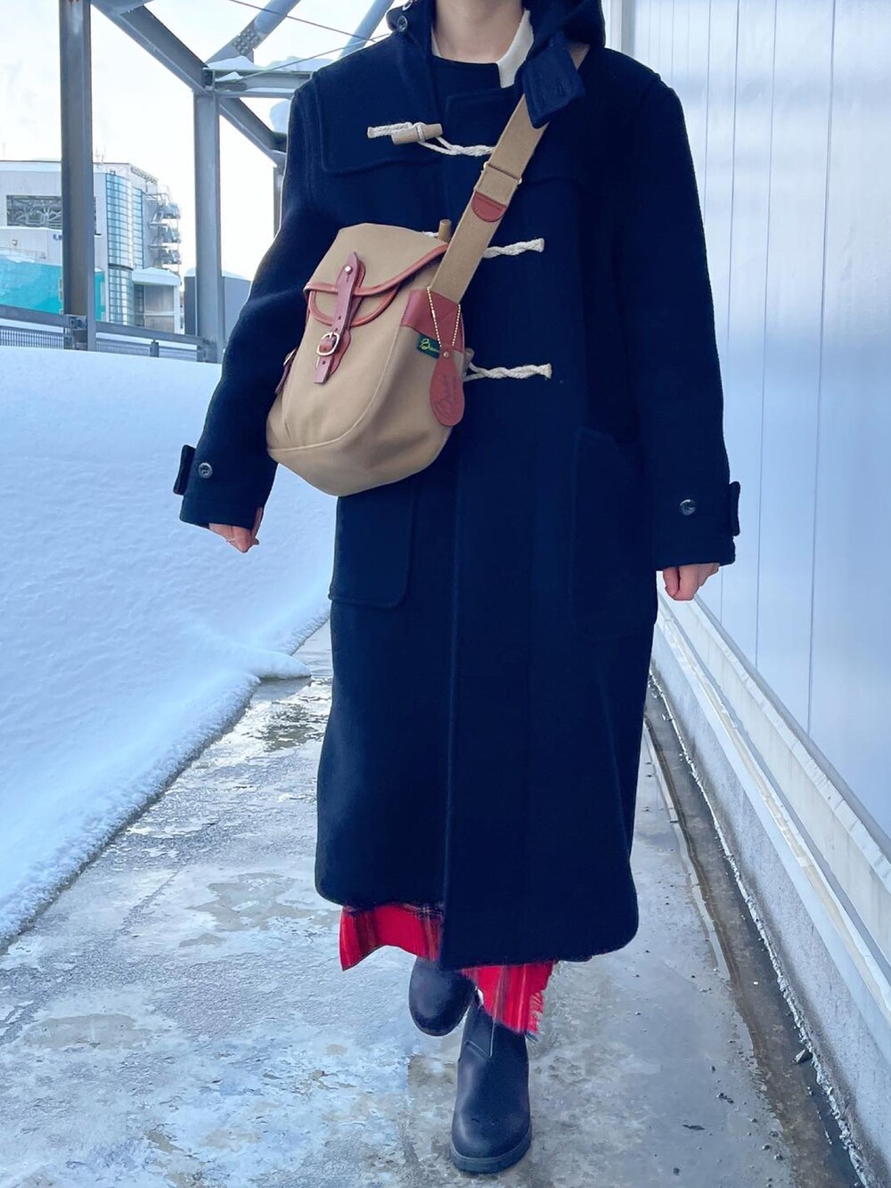 ベージュ系のショルダーバッグ、ブラック系のダッフルコート、レッド系のスカートを着用したレディースの冬コーディネートの2枚目の写真