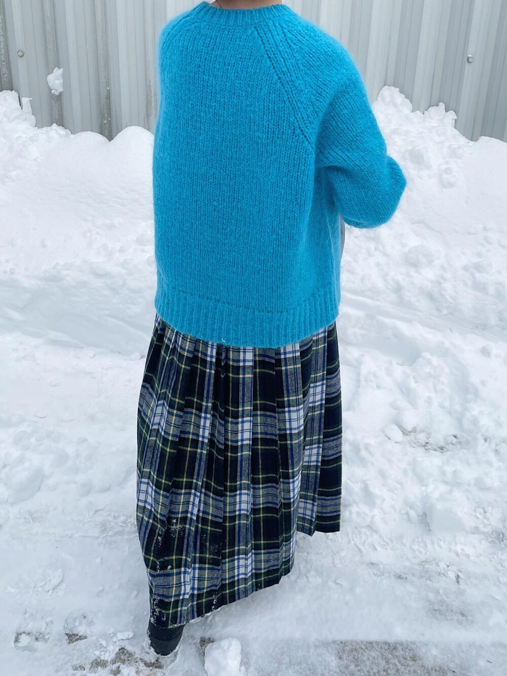 ブルー系のニット/セーター、ブラック系のボストンバッグ、グリーン系のスカートを着用したレディースの冬コーディネートの5枚目の写真