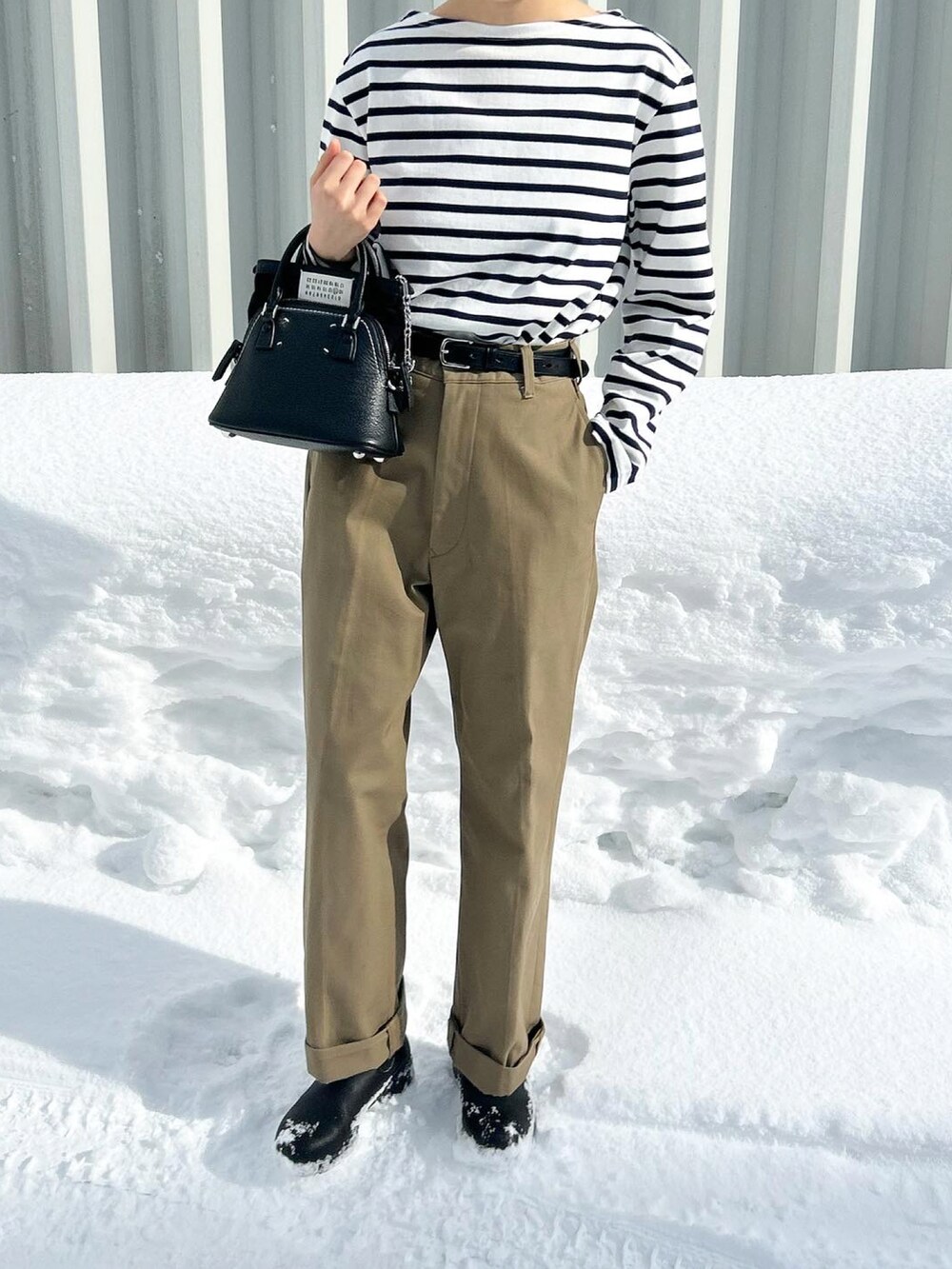 ブラック系のショルダーバッグ、ベージュ系のチノパンツ、ブラック系のブーツを着用したレディースの冬コーディネートの2枚目の写真