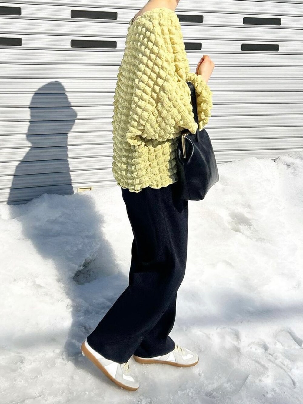 ブラック系のハンドバッグ、ブルー系のスラックス、ホワイト系のスニーカーを着用したレディースの春コーディネートの2枚目の写真