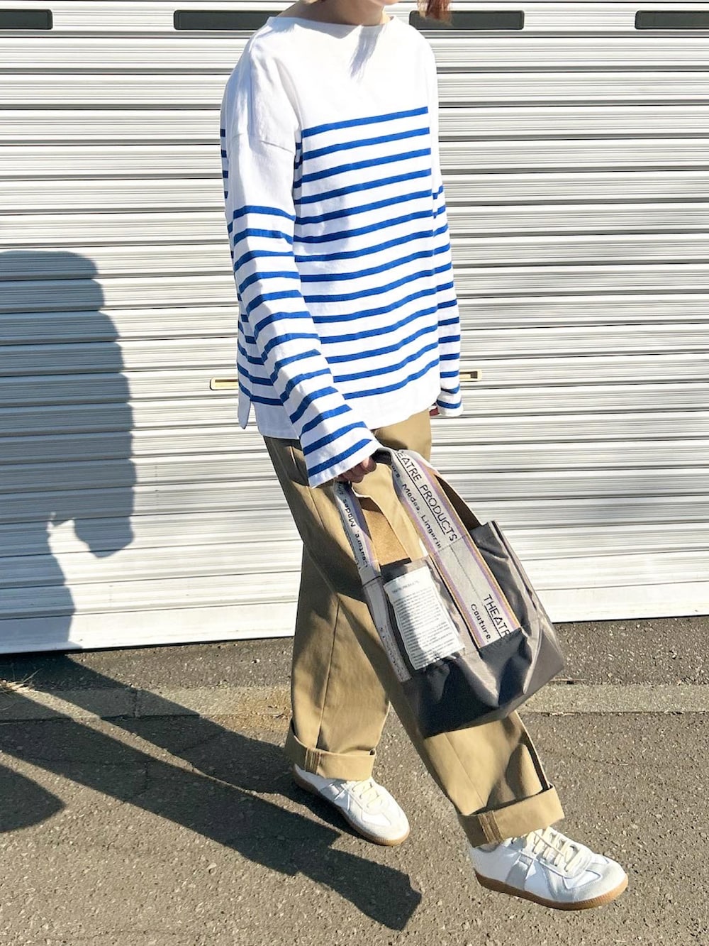 ブラック系のTシャツ/カットソー、ベージュ系のトートバッグ、ベージュ系のチノパンツを着用したレディースの春コーディネートの3枚目の写真