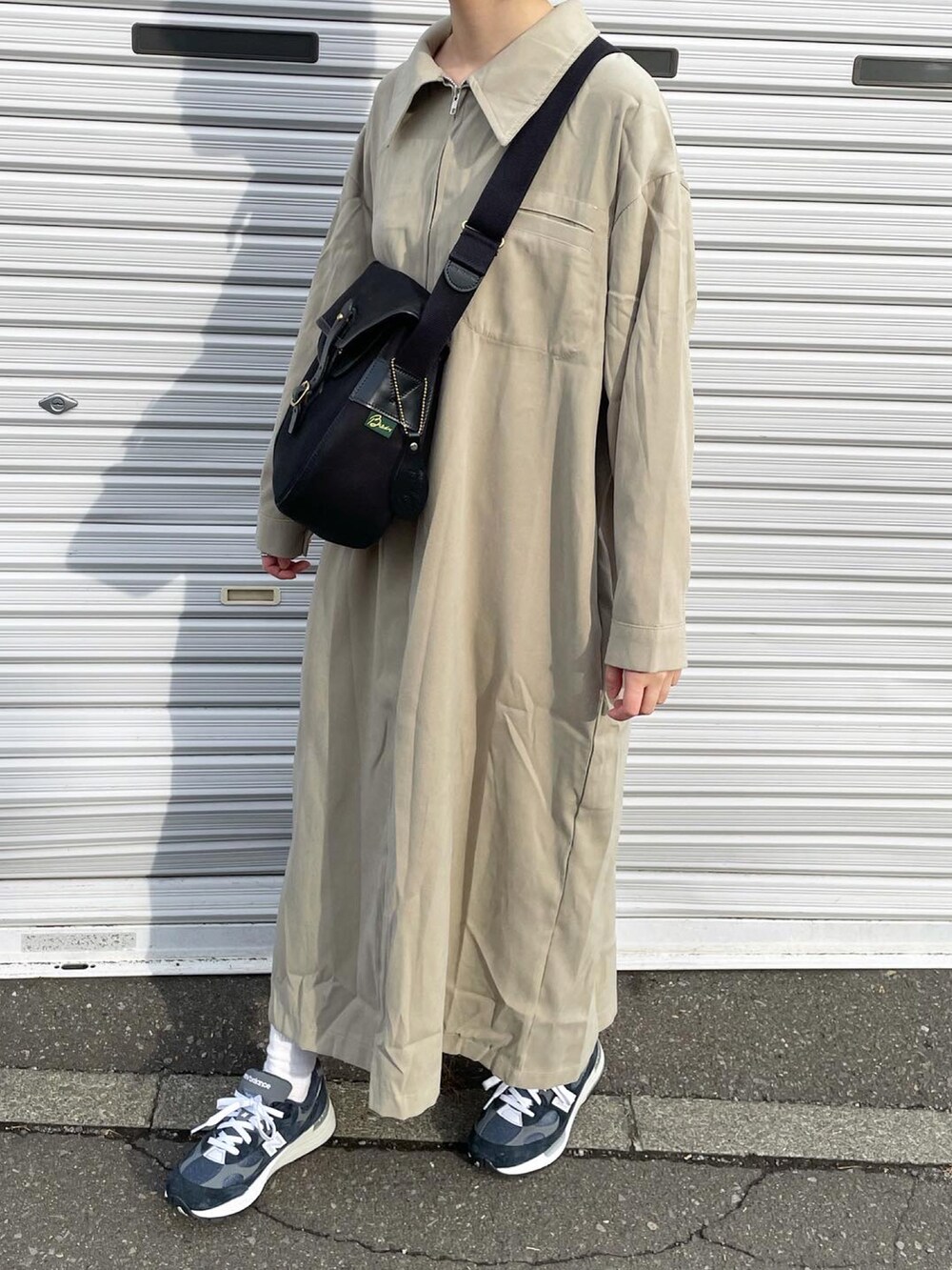 ブラック系のショルダーバッグ、ブルー系のスニーカーを着用したレディースの秋コーディネートの2枚目の写真