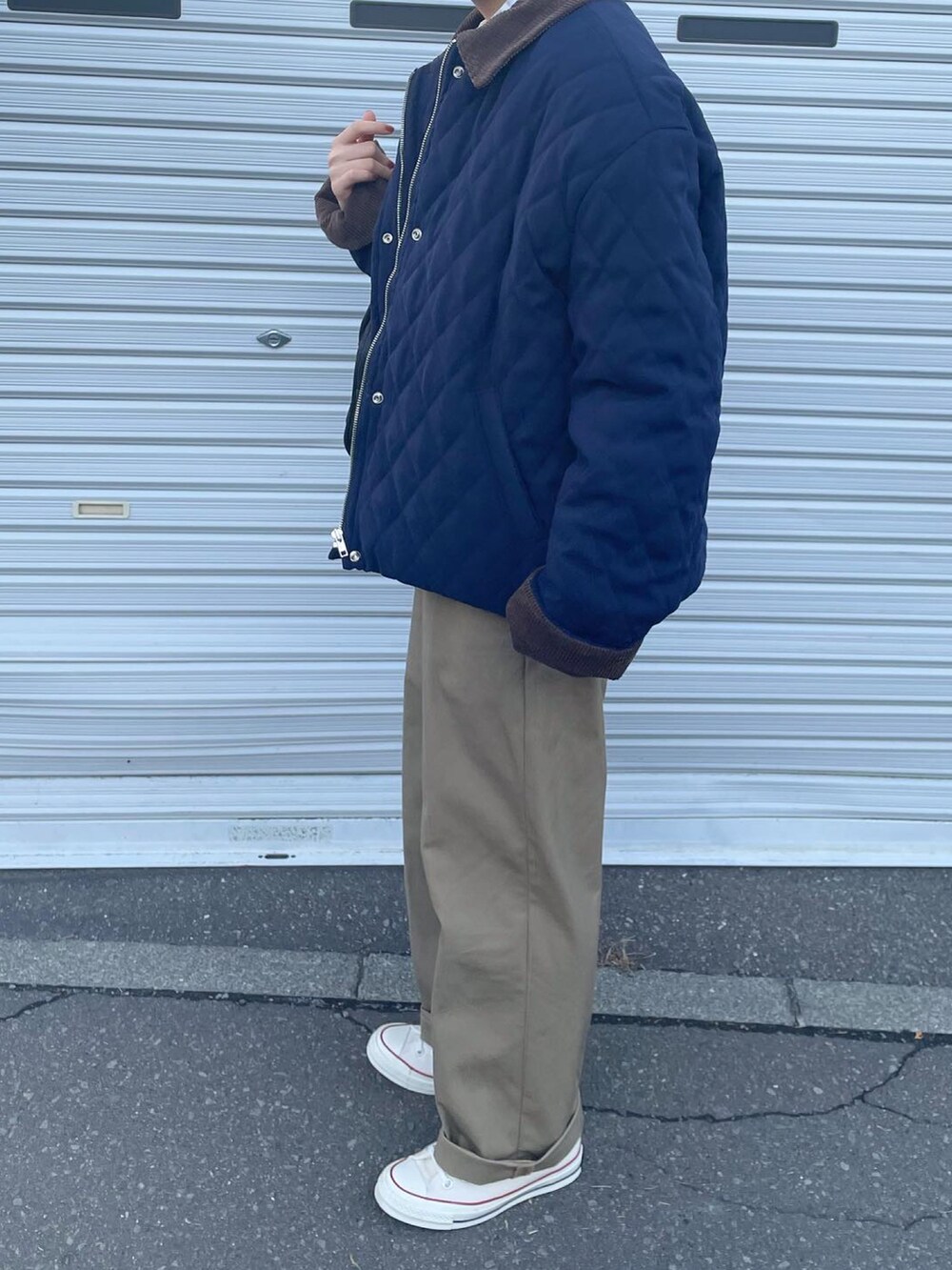 ベージュ系のチノパンツ、ホワイト系のスニーカー、ブラック系のボストンバッグを着用したレディースの冬コーディネートの2枚目の写真