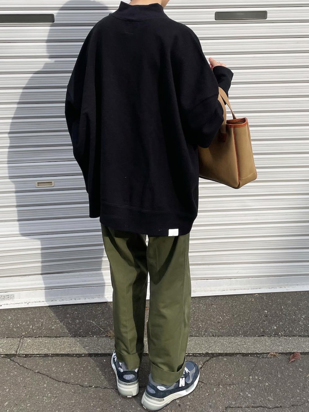 ブラック系のスウェット、ブラウン系のハンドバッグ、ブルー系のスニーカーを着用したレディースの秋コーディネートの4枚目の写真