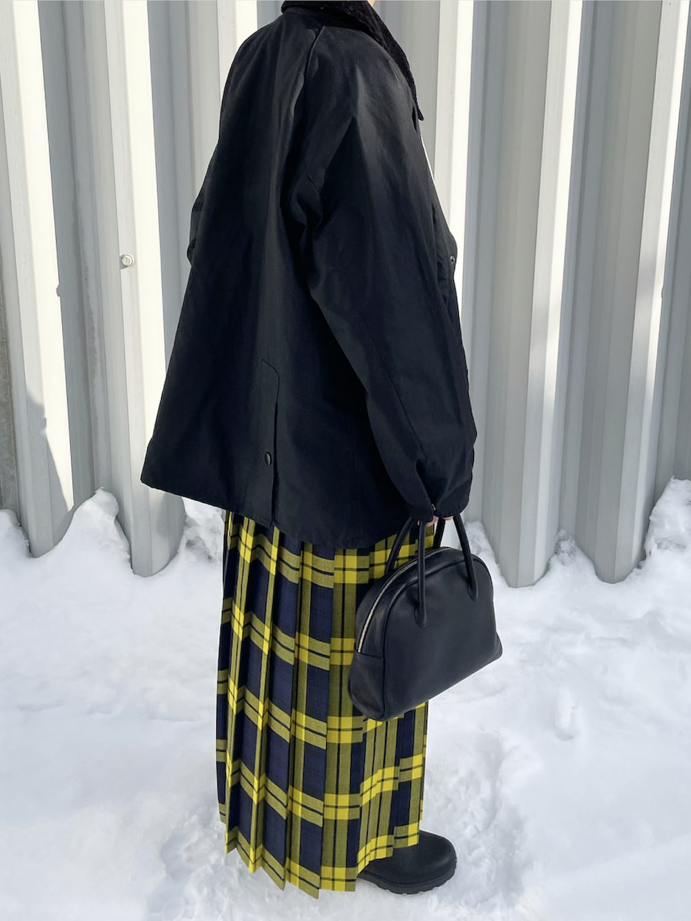 ブラック系のブルゾン、イエロー系のスカート、ブラック系のボストンバッグを着用したレディースの冬コーディネートの2枚目の写真