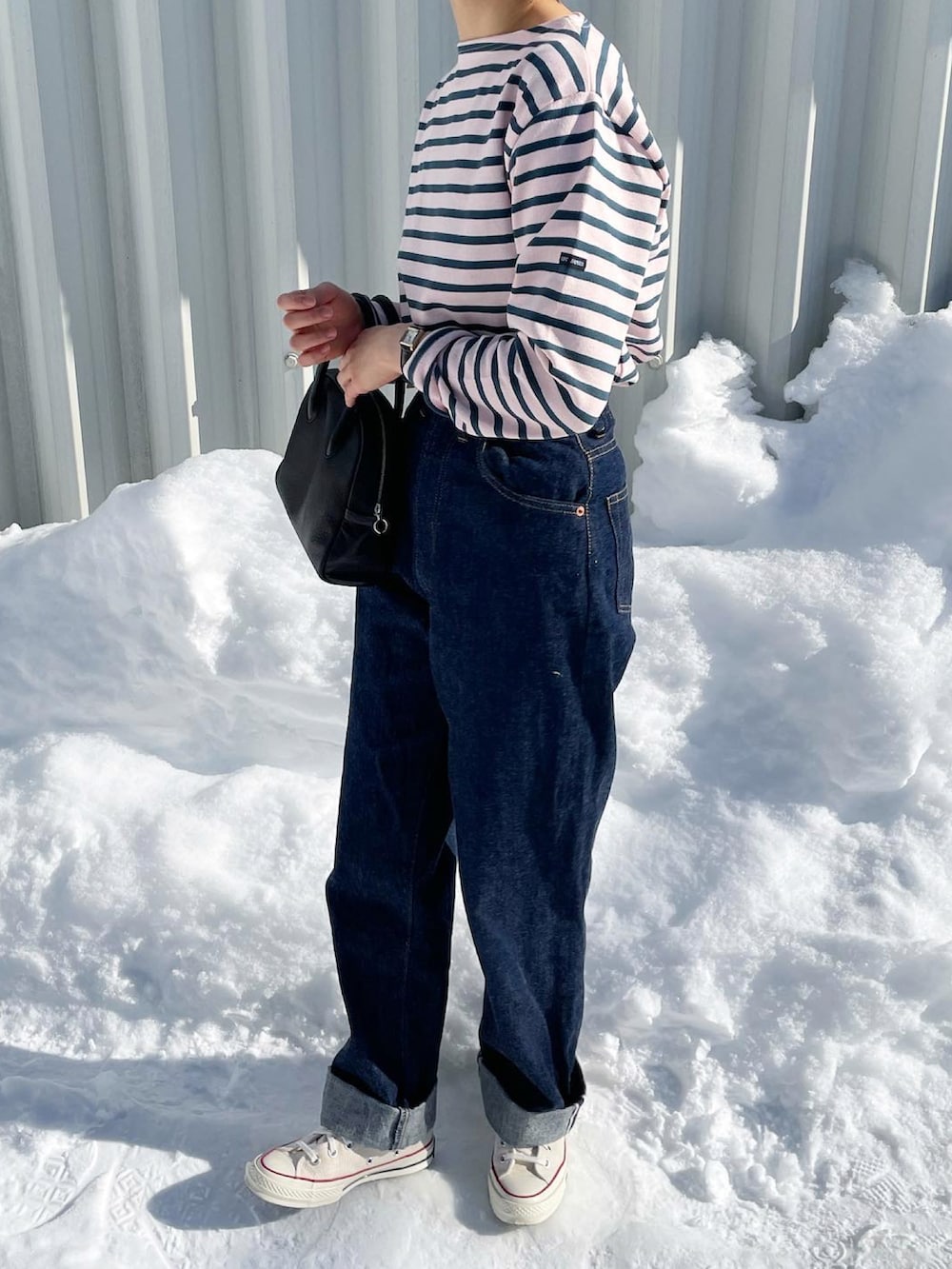 ブルー系のデニムパンツ、ブラック系のボストンバッグ、ホワイト系のスニーカーを着用したレディースの冬コーディネートの2枚目の写真