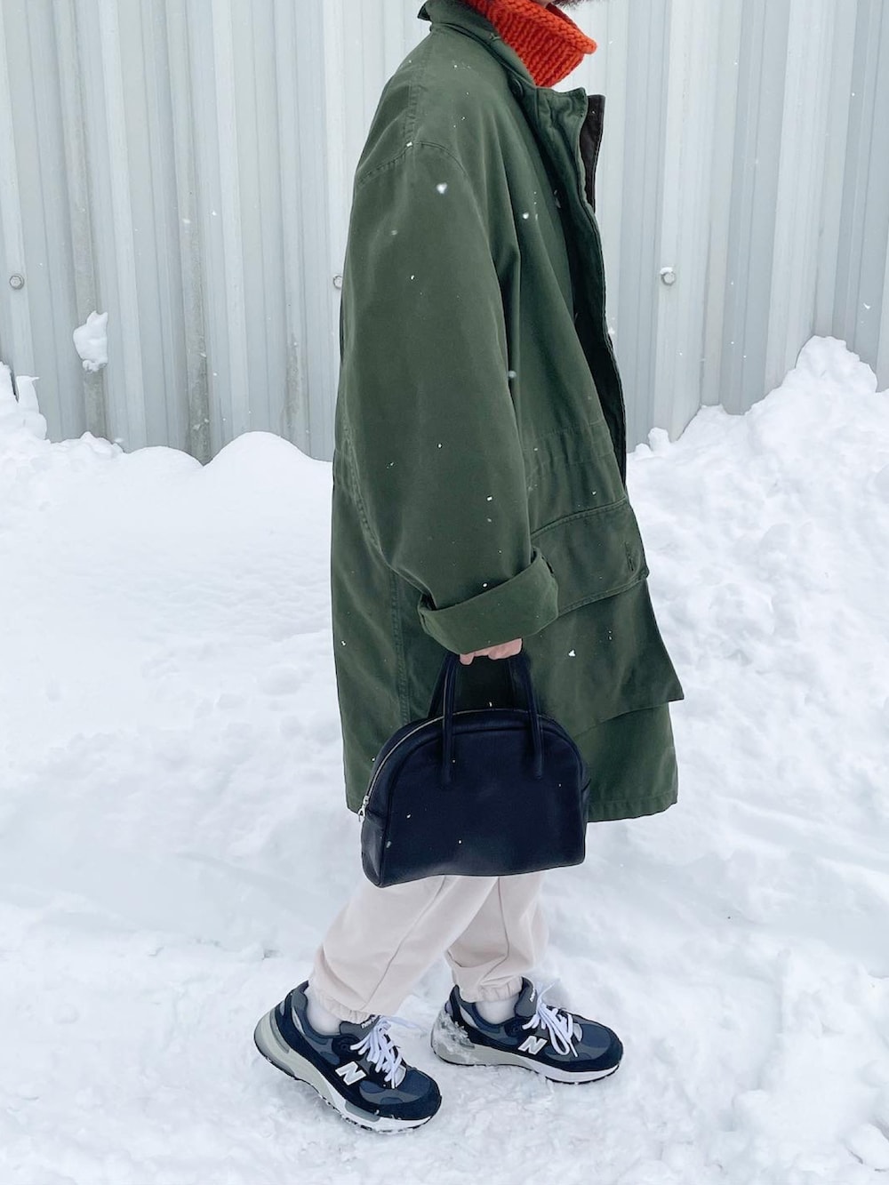 ブルー系のスニーカー、グリーン系のその他アウター、オレンジ系のニット/セーターを着用したレディースの冬コーディネートの2枚目の写真