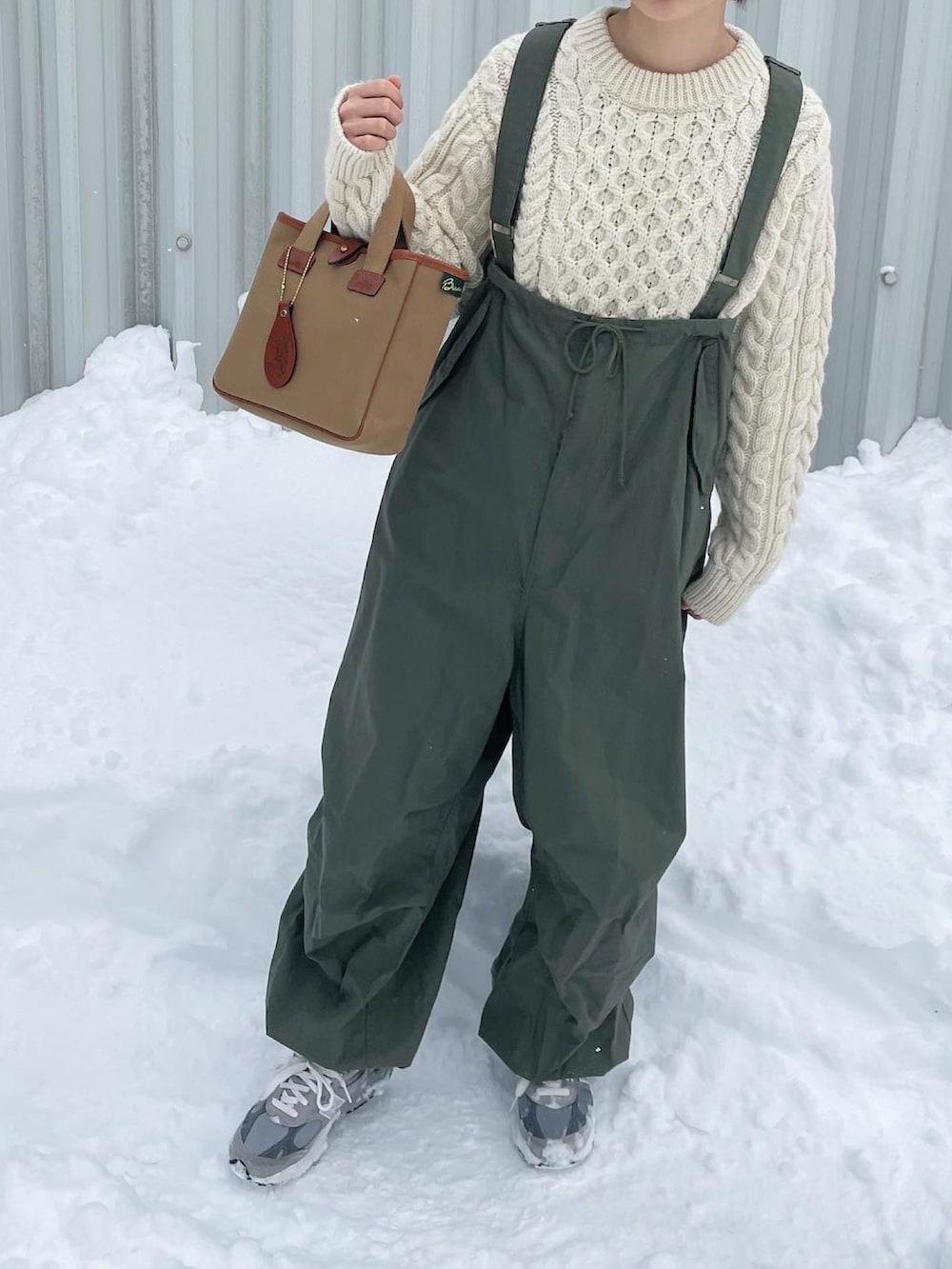 グリーン系のカーゴパンツ、ホワイト系のニット/セーター、グレー系のスニーカーを着用したレディースの冬コーディネートの2枚目の写真