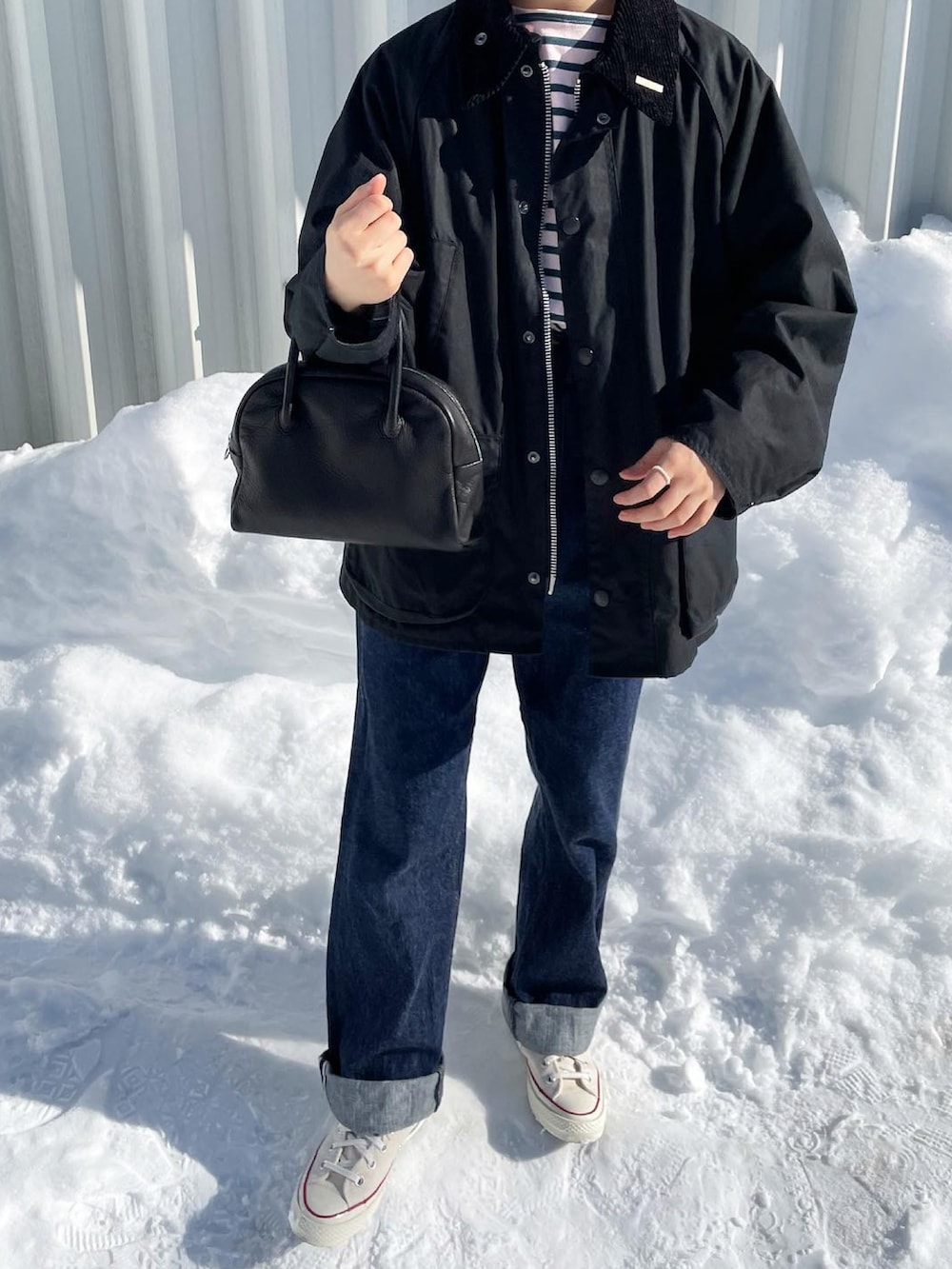 ブルー系のデニムパンツ、ブラック系のボストンバッグ、ホワイト系のスニーカーを着用したレディースの冬コーディネートの4枚目の写真