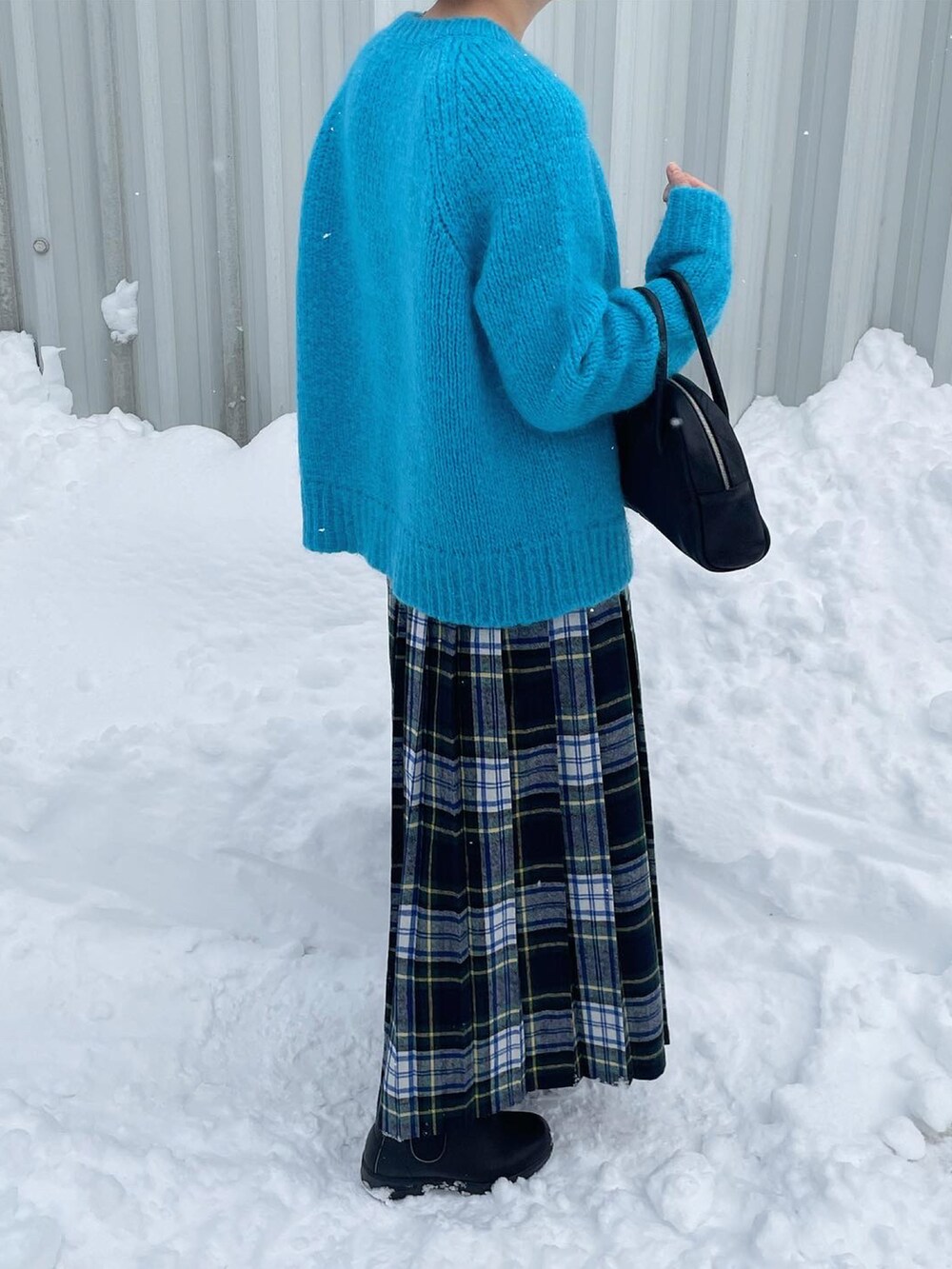 ブルー系のニット/セーター、ブラック系のボストンバッグ、グリーン系のスカートを着用したレディースの冬コーディネートの2枚目の写真