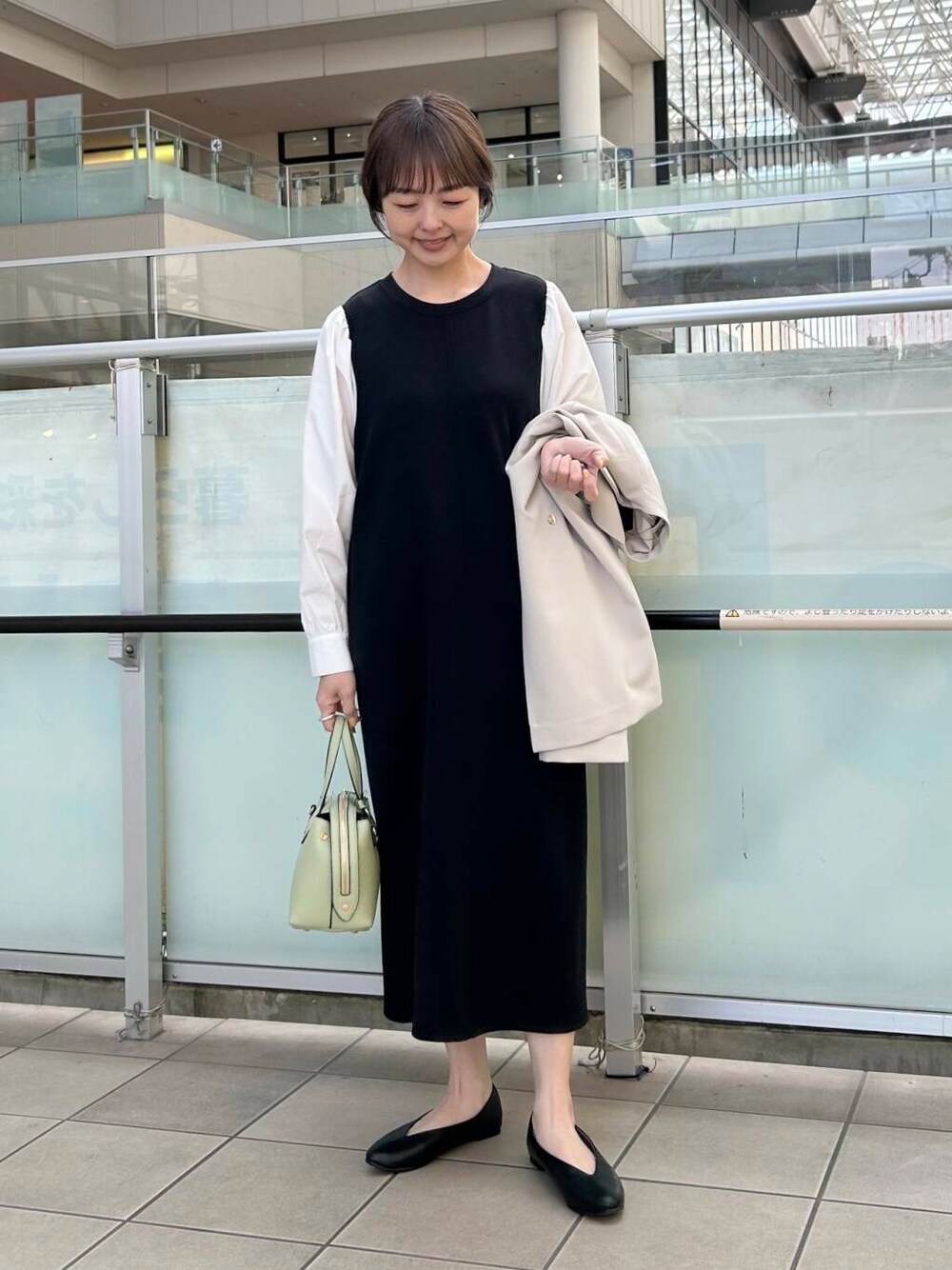 ブラック系のパンプス、ベージュ系のその他アウター、ブラック系のワンピースを着用したレディースの春コーディネートの4枚目の写真
