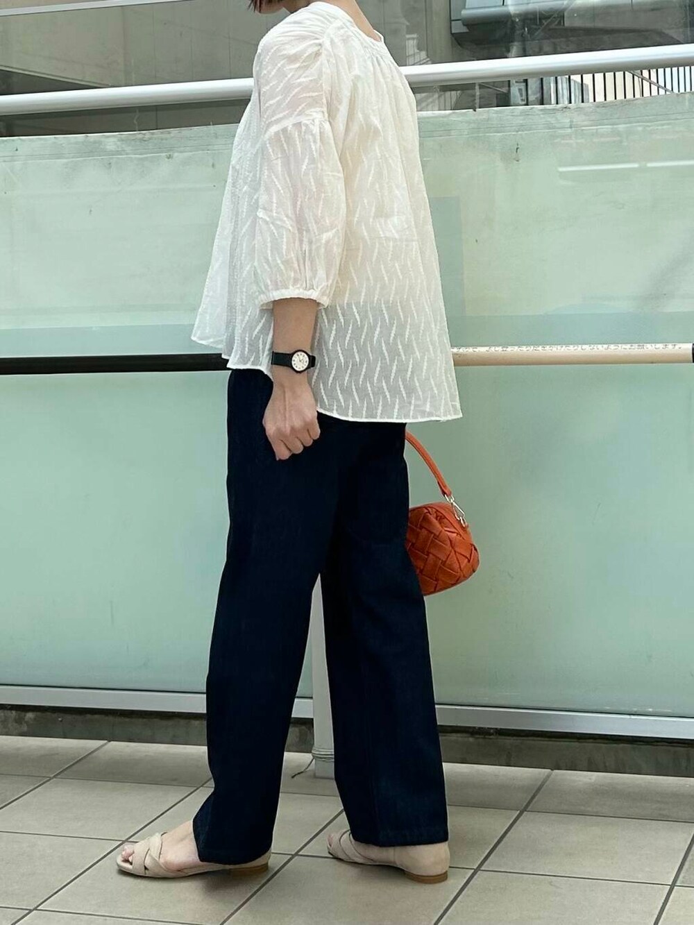 ベージュ系のサンダル、オレンジ系のショルダーバッグ、ブルー系のデニムパンツを着用したレディースの夏コーディネートの3枚目の写真