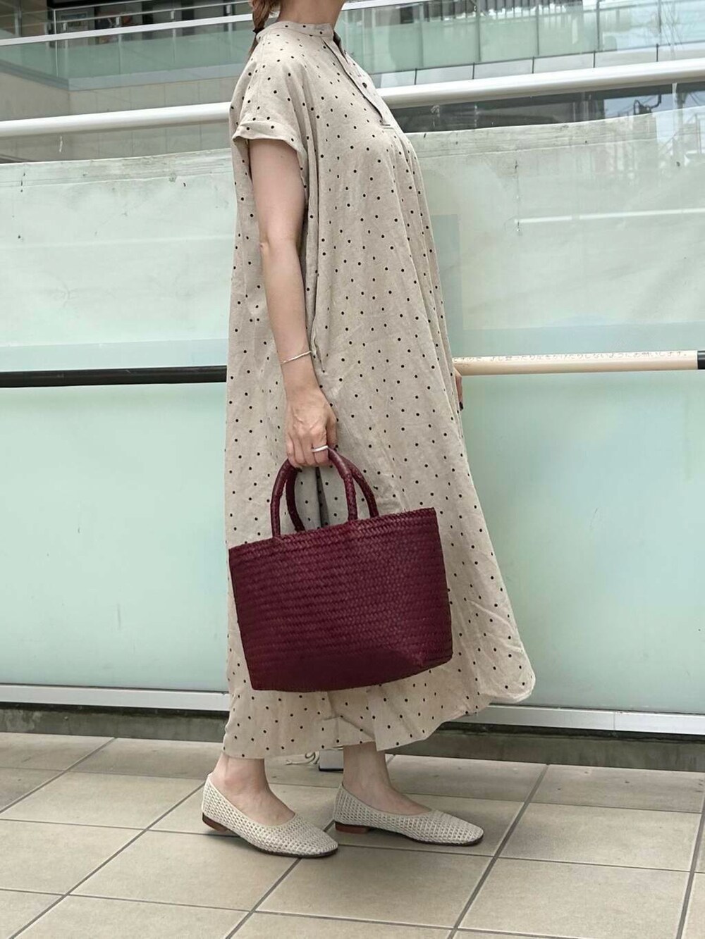 レッド系のトートバッグ、ホワイト系のバレエシューズ、ベージュ系のワンピースを着用したレディースの夏コーディネートの2枚目の写真