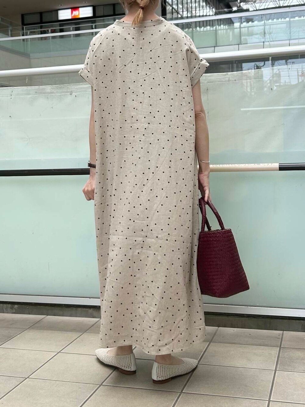 レッド系のトートバッグ、ホワイト系のバレエシューズ、ベージュ系のワンピースを着用したレディースの夏コーディネートの4枚目の写真