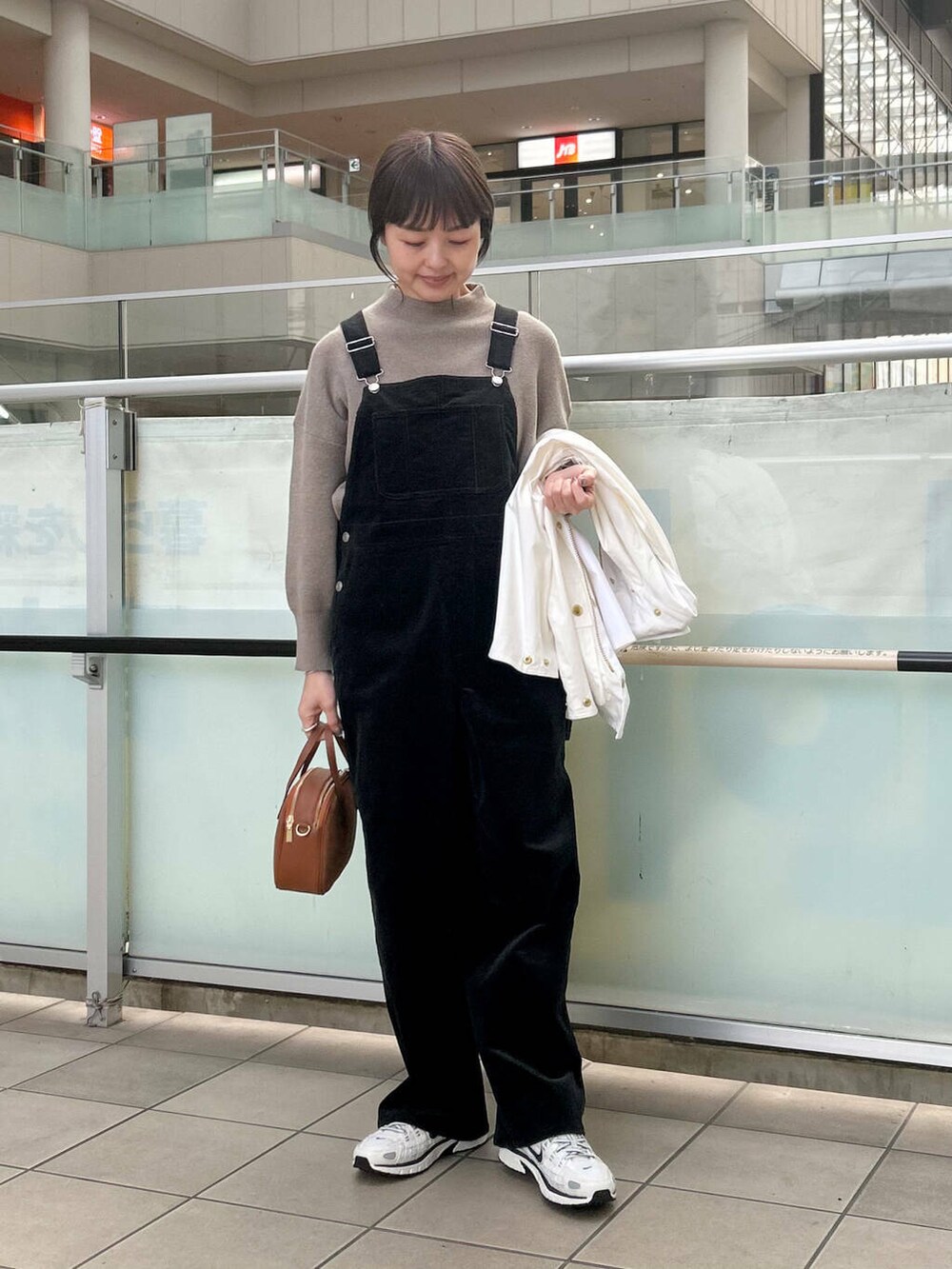 ブラウン系のショルダーバッグ、ベージュ系のニット/セーター、ブラック系のサロペット/オーバーオールを着用したレディースの冬コーディネートの3枚目の写真