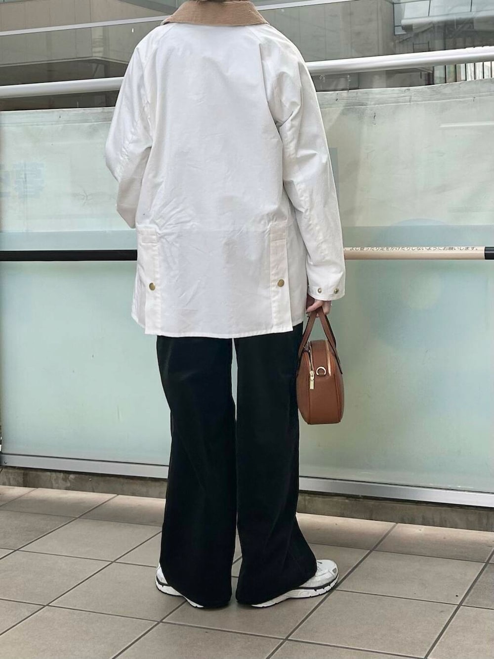 ブラウン系のショルダーバッグ、ベージュ系のニット/セーター、ブラック系のサロペット/オーバーオールを着用したレディースの冬コーディネートの2枚目の写真