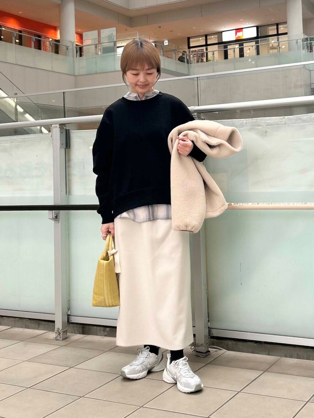 イエロー系のトートバッグ、グレー系のシャツ/ブラウス、シルバー系のスニーカーを着用したレディースの冬コーディネートの4枚目の写真
