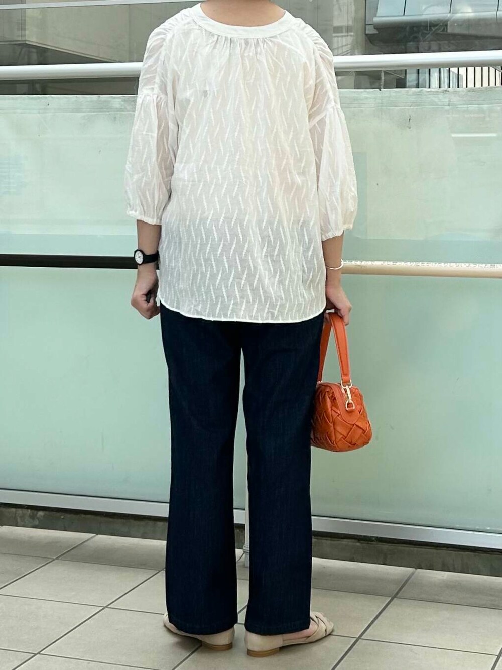 ベージュ系のサンダル、オレンジ系のショルダーバッグ、ブルー系のデニムパンツを着用したレディースの夏コーディネートの4枚目の写真