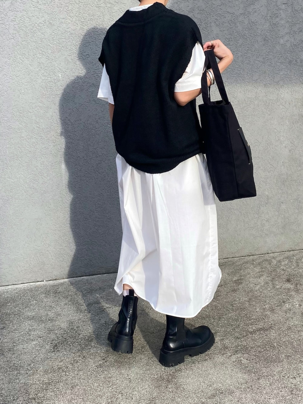 グレー系のトートバッグ、ブラック系のブーツを着用したレディースの秋コーディネートの2枚目の写真